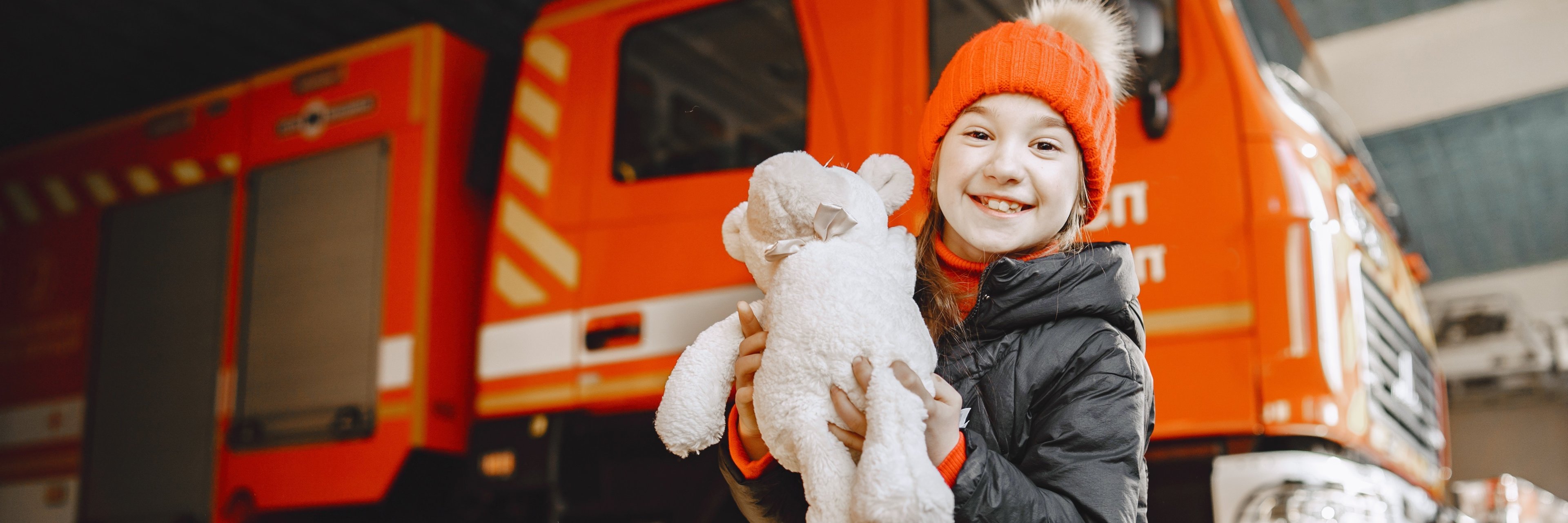 Girl near fire truck with a toy in hand Girl near fire truck with a toy in hand